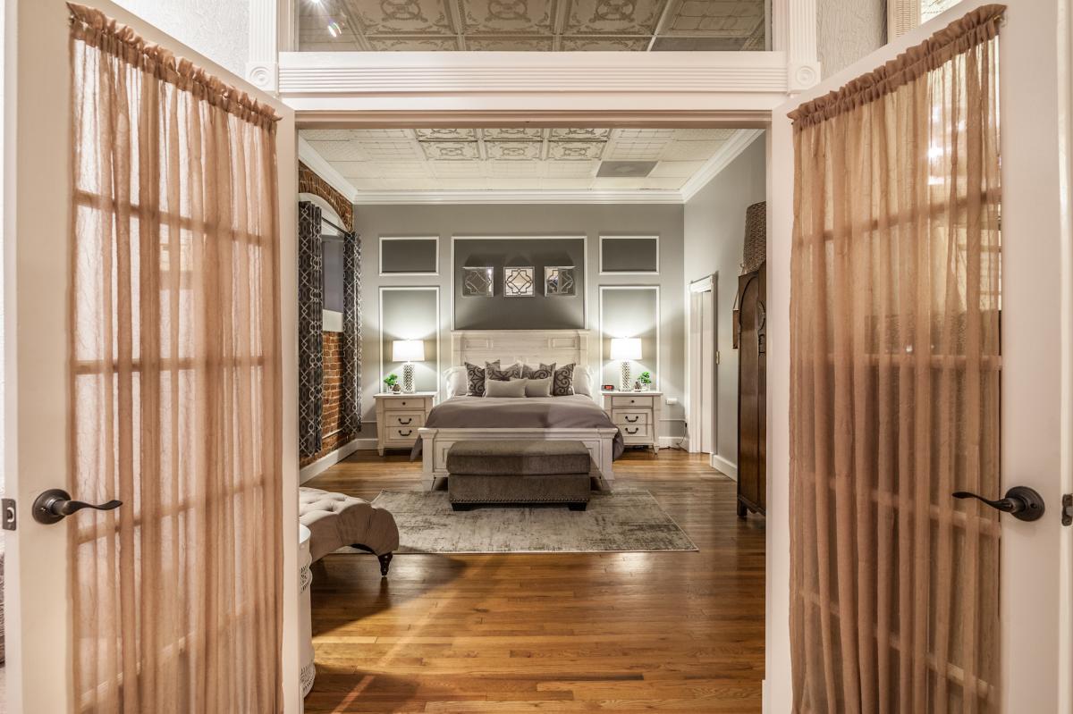 a master bedroom located through french doors with a curtain